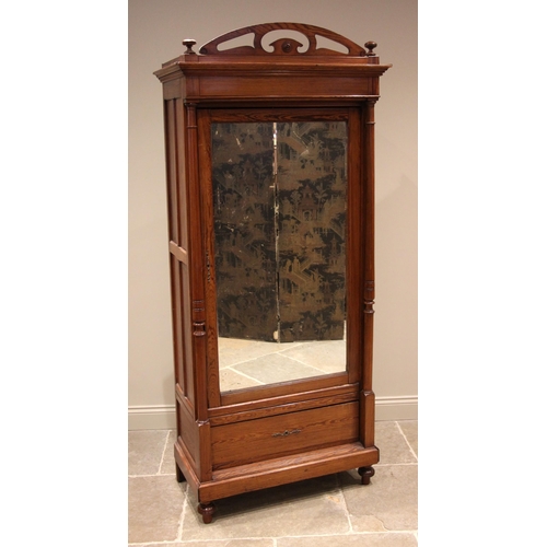 1092 - A French pitch pine single wardrobe, late 19th/early 20th century, the arched openwork pediment over... 