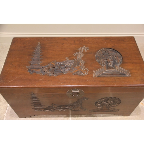 1095 - A Chinese camphor wood blanket chest, mid 20th century, the hinged cover carved in deep relief with ... 