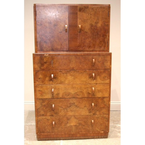 1102 - A 1930's Art Deco figured walnut tall boy, the quarter veneered top over an arrangement of two cupbo... 