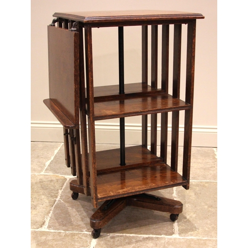 1107 - An early 20th century oak revolving bookcase, the rectangular moulded top extended with an articulat... 