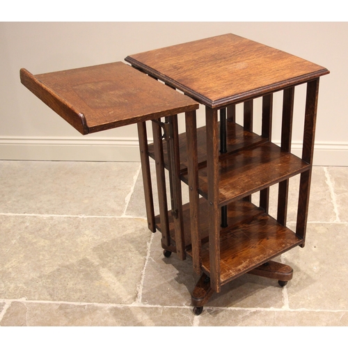 1107 - An early 20th century oak revolving bookcase, the rectangular moulded top extended with an articulat... 