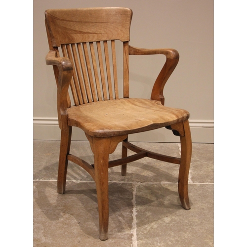 1111 - An early 20th century beech captains/desk chair, with a concave lath back over a shaped seat, cabrio... 