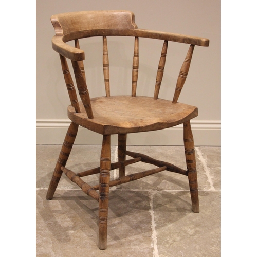 1112 - An early 20th century elm and beech wood captains desk chair, the curved top rail upon eight ring tu... 