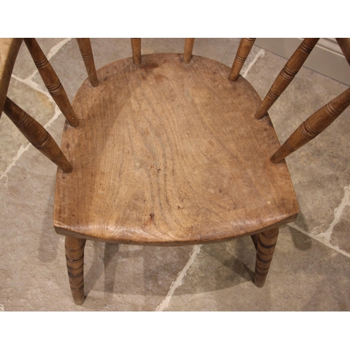 1112 - An early 20th century elm and beech wood captains desk chair, the curved top rail upon eight ring tu... 