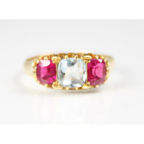 309 - An aquamarine and synthetic ruby three stone ring, the central cushion cut aquamarine with a cushion... 