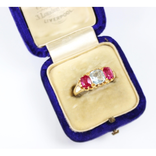 309 - An aquamarine and synthetic ruby three stone ring, the central cushion cut aquamarine with a cushion... 