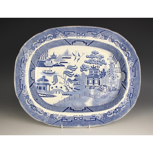 680 - A blue and white meat plate, 19th century, decorated in the willow pattern, 44.5cm wide, along with ... 