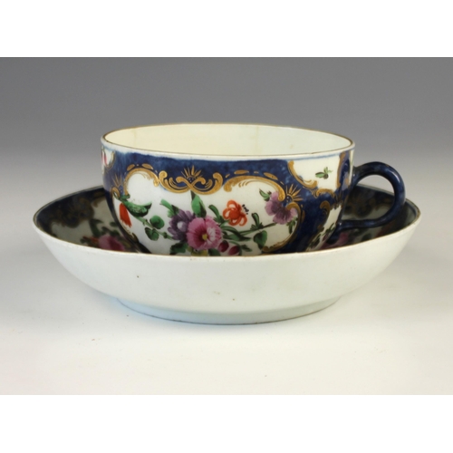 683 - A Worcester first period teacup and saucer, circa 1770, decorated with floral reserves to a cobalt g... 