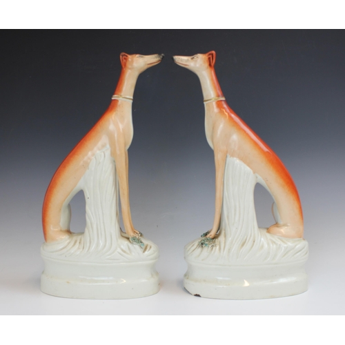 723 - A pair of Staffordshire greyhounds, 19th century, modelled seated, beside a tree stump with caught g... 