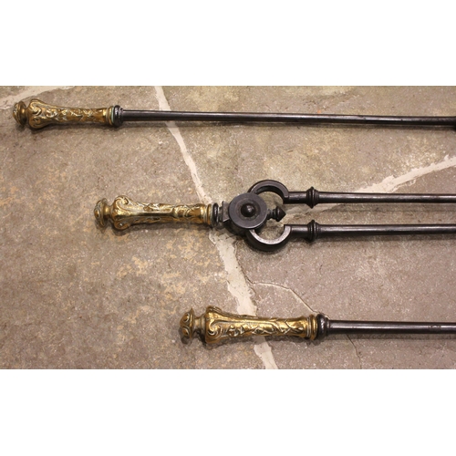 831 - A set of three George III steel and brass fire implements, each with a brass button terminal extendi... 