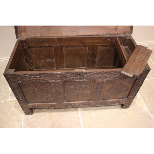 987 - A late 17th/early 18th century carved oak coffer, the four panel cover with hook and eye hinges open... 