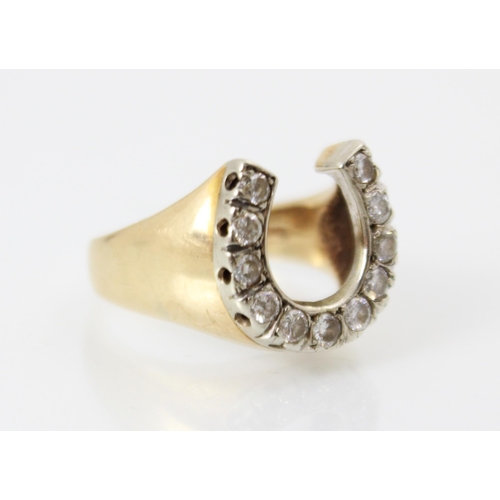 220 - A diamond set yellow metal dress ring, the white metal set round cut diamonds in a horseshoe design,... 