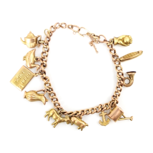 233 - A yellow metal charm bracelet, the curb link bracelet suspending eleven yellow metal and gold colour... 