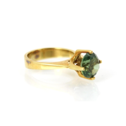 270 - A yellow metal and green tourmaline set dress ring, the round cut tourmaline set in high four claw s... 