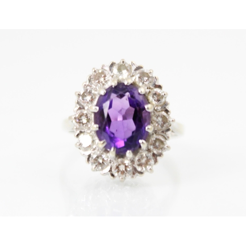 272 - An amethyst and diamond cluster ring, the oval cut amethyst within a surround of twelve round cut di... 