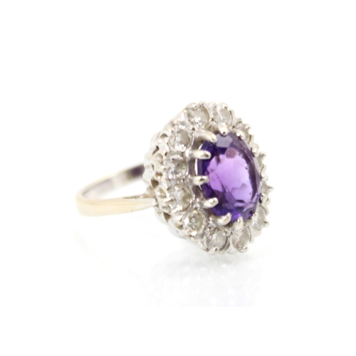 272 - An amethyst and diamond cluster ring, the oval cut amethyst within a surround of twelve round cut di... 