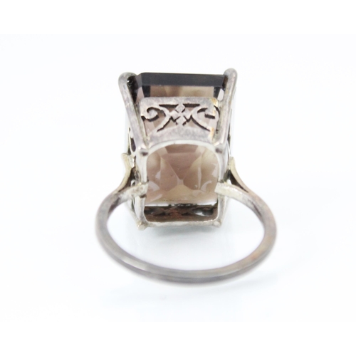 302 - A smokey quartz dress ring, the rectangular cut quartz claw set in silver coloured metal leading to ... 