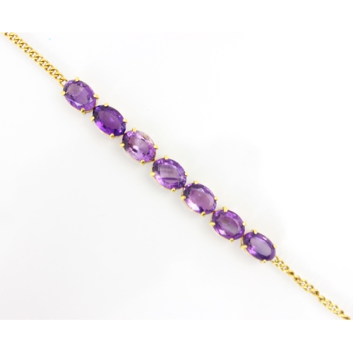 303 - An amethyst set yellow metal bracelet, the seven oval cut amethysts in a four claw setting edge, ope... 