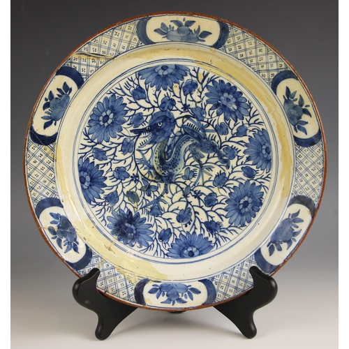 725 - A Delft plate, late 17th century, the well decorated with mythical beast among flora and foliage, th... 