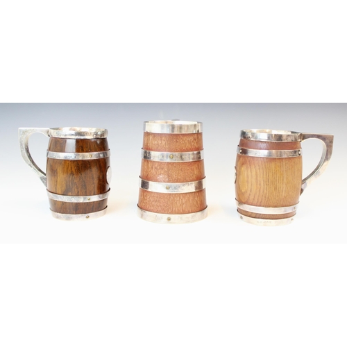 99 - A near pair of silver plated wooden mugs, of barrel form with silver plate banded detail and central... 