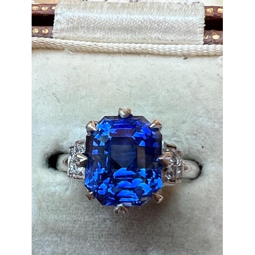 291 - An early 20th century sapphire and diamond ring, the emerald cut sapphire within white metal eight c... 