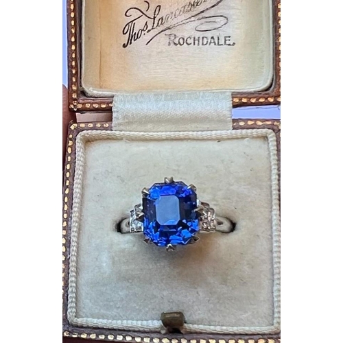 291 - An early 20th century sapphire and diamond ring, the emerald cut sapphire within white metal eight c... 