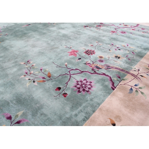 933 - A very large Chinese wool carpet, the central green field adorned with exotic birds upon flowering b... 