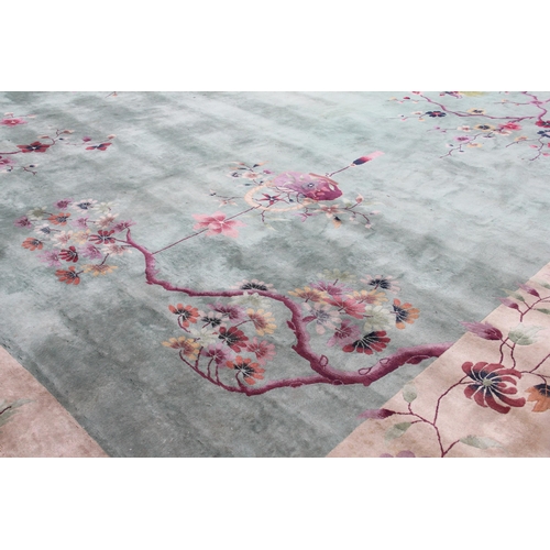 933 - A very large Chinese wool carpet, the central green field adorned with exotic birds upon flowering b... 