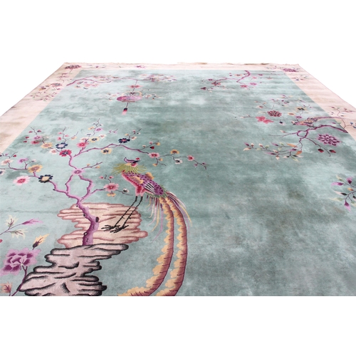 933 - A very large Chinese wool carpet, the central green field adorned with exotic birds upon flowering b... 