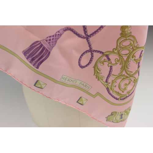 433 - An Hermes silk scarf, in the 'Les Cles' pattern, in pink, lilac and gold tones, with rolled hems, 89... 