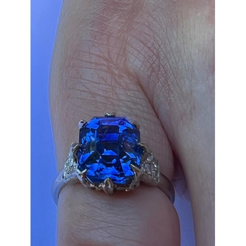 291 - An early 20th century sapphire and diamond ring, the emerald cut sapphire within white metal eight c... 