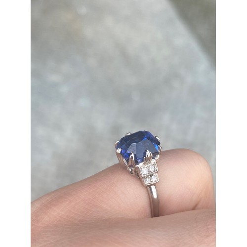 291 - An early 20th century sapphire and diamond ring, the emerald cut sapphire within white metal eight c... 