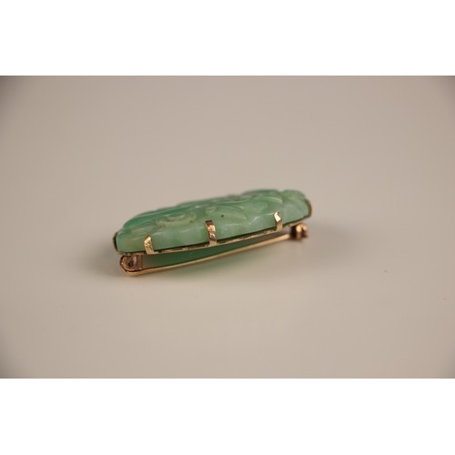 208 - A Birks Ellis ‘jade’ brooch, the carved oval panel with scalloped edge depicting floral detail, with... 