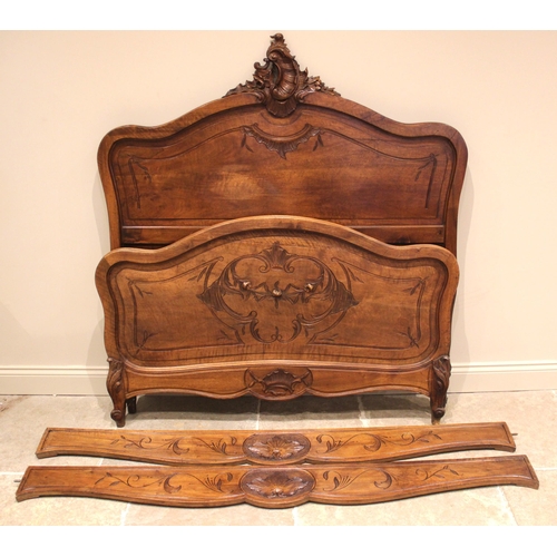 1032 - A French Louis XV style walnut bed, early 20th century, the quarter veneered shaped headboard with a... 