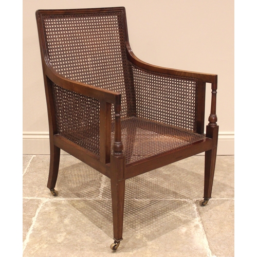 1036 - An Edwardian mahogany bergere library chair, the rectangular cane work back extending to down swept ... 