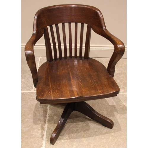 1037 - An early 20th century oak office/desk chair, the concave lath back extending to down swept arms over... 