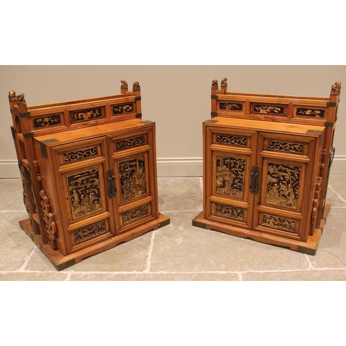 1067 - A pair of Chinese pine marriage chests, late 20th century, the relief moulded doors highlighted in g... 