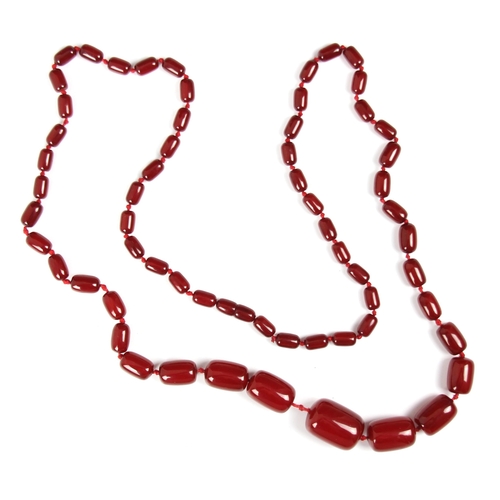 157 - A string of cherry coloured 'amber' beads, the graduated barrel shaped beads with plastic screw fast... 