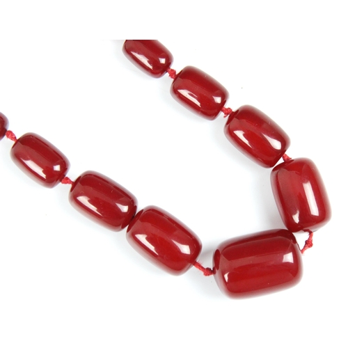 157 - A string of cherry coloured 'amber' beads, the graduated barrel shaped beads with plastic screw fast... 