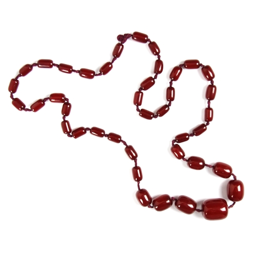 158 - A string of cherry coloured 'amber' beads, the graduated barrel shaped beads strung upon red string,... 