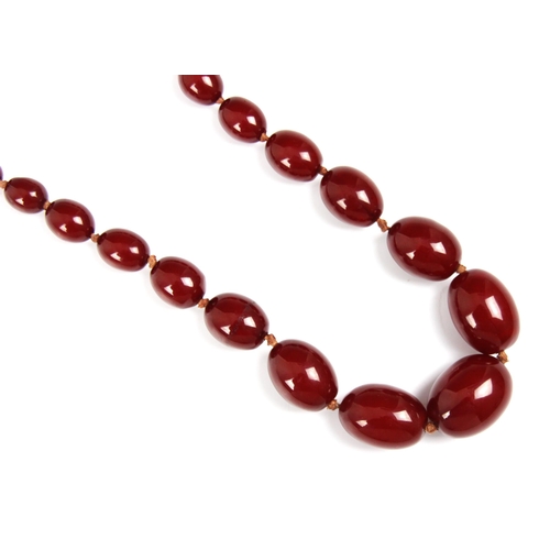 159 - A string of cherry coloured 'amber' beads, the graduated beads strung upon string, largest bead 2.9c... 