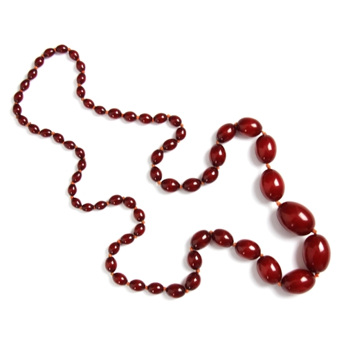 160 - A string of cherry coloured 'amber' beads, the graduated oval beads strung upon string, largest bead... 