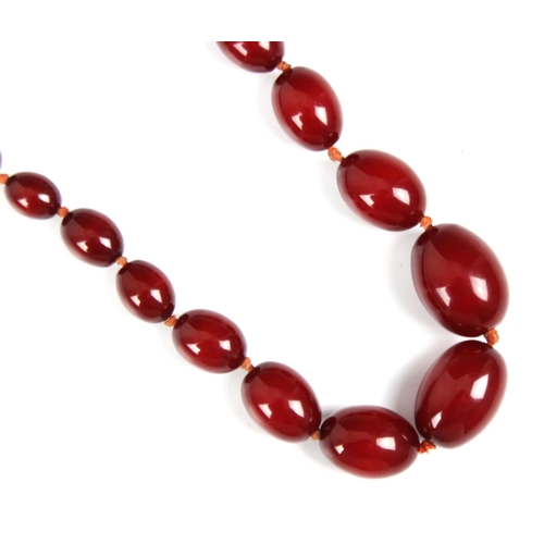 160 - A string of cherry coloured 'amber' beads, the graduated oval beads strung upon string, largest bead... 