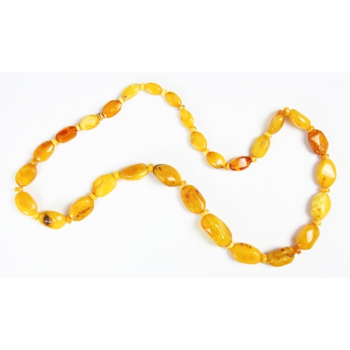 161 - A string of butterscotch coloured amber beads, the graduated non uniform shaped beads interspersed w... 