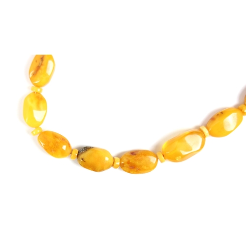 161 - A string of butterscotch coloured amber beads, the graduated non uniform shaped beads interspersed w... 