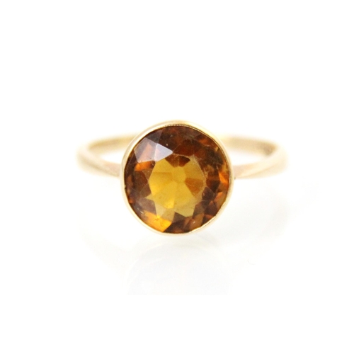 170 - A 20th century citrine set ring, the round cut citrine with a rubover mount leading to plain polishe... 