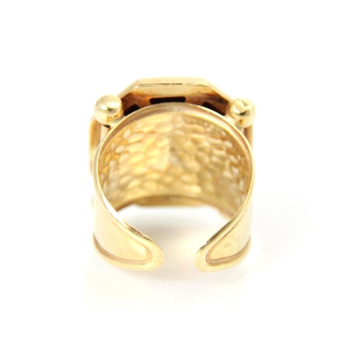 201 - A yellow metal dress ring, the octagonal shaped head of the ring with engraved detail depicting head... 