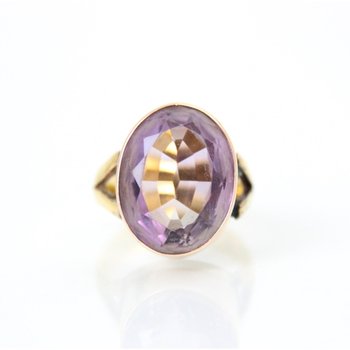 211 - An amethyst set dress ring, the oval cut amethyst within yellow metal rubover mount, leading to asso... 