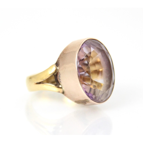 211 - An amethyst set dress ring, the oval cut amethyst within yellow metal rubover mount, leading to asso... 