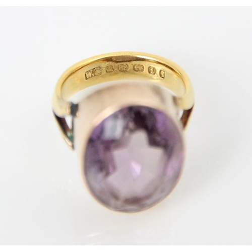 211 - An amethyst set dress ring, the oval cut amethyst within yellow metal rubover mount, leading to asso... 